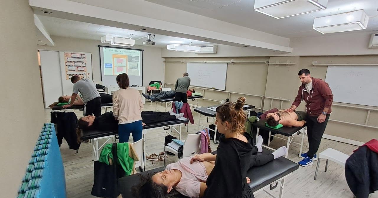 Alumnos practicando palpación abdominal en camillas durante la formación VM1